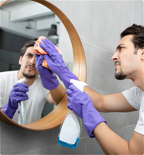 man cleaning bathroom mirror at home